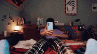 a person laying on a bed holding a cell phone