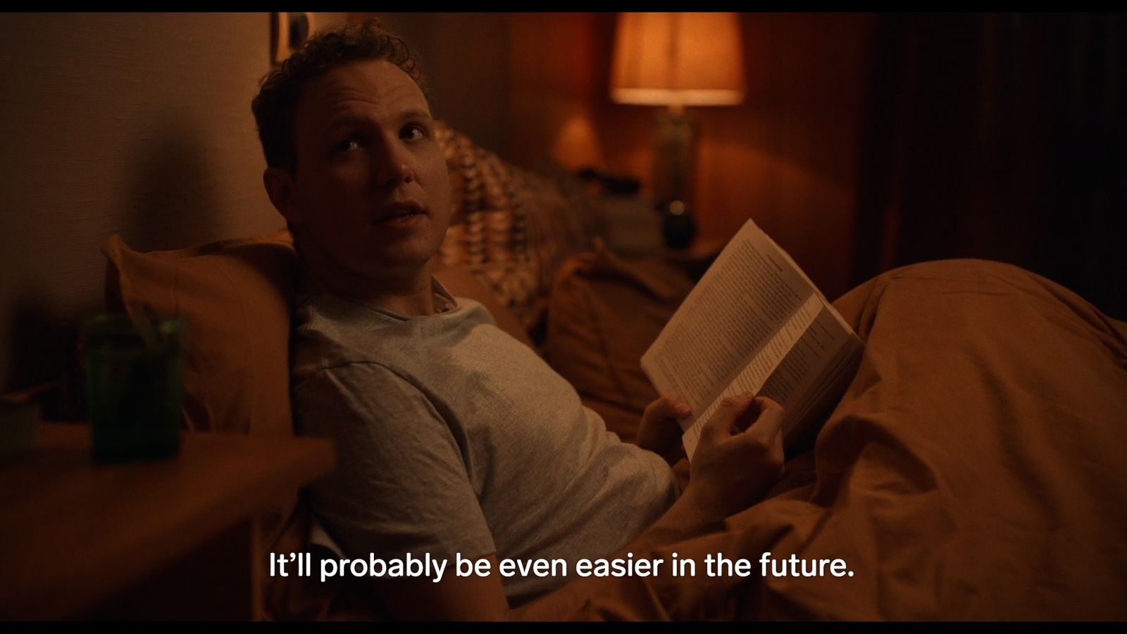 a man laying in bed reading a book