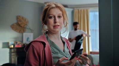 a woman standing in a living room holding a cell phone