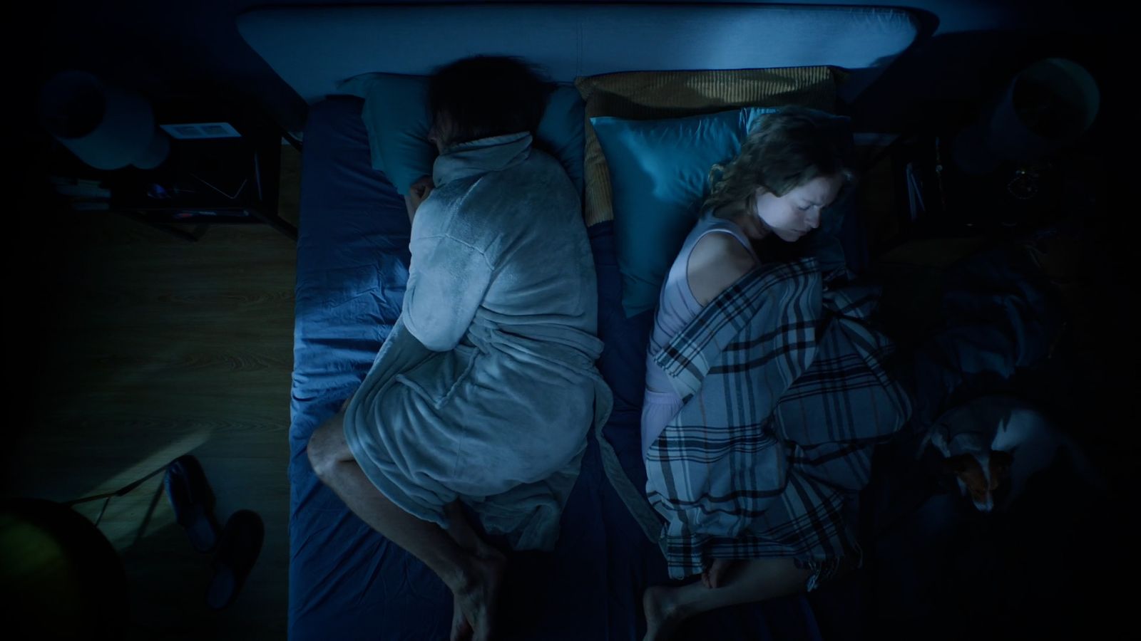 a man and a woman sleeping in bed at night