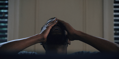 a man sitting in a chair with his hands on his head