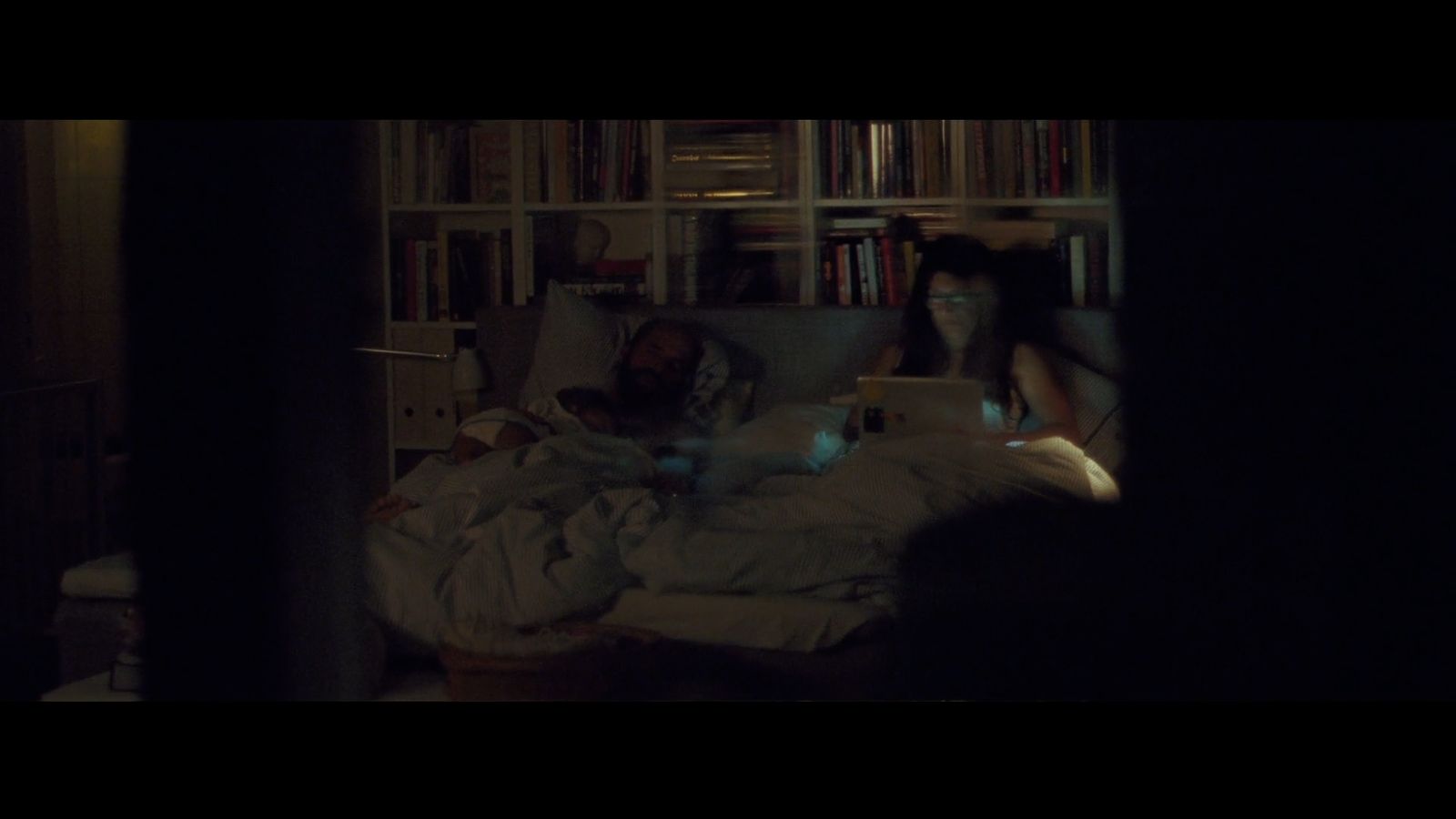 a man and a woman sitting on a bed in a dark room