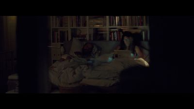 a man and a woman sitting on a bed in a dark room