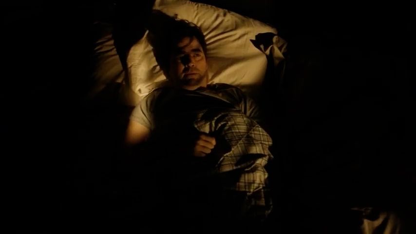 a man laying in a bed in the dark