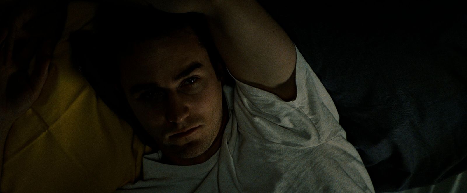 a man laying on a bed in the dark