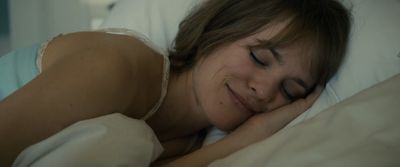 a woman laying in bed with her eyes closed