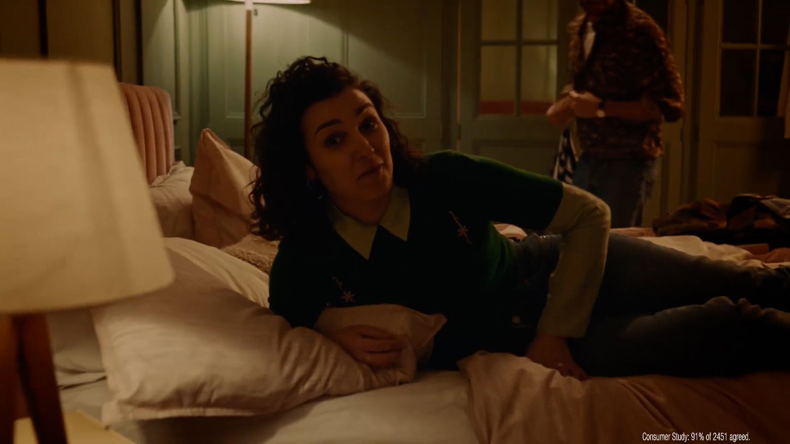 a woman laying on top of a bed next to a lamp