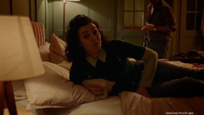 a woman laying on top of a bed next to a lamp