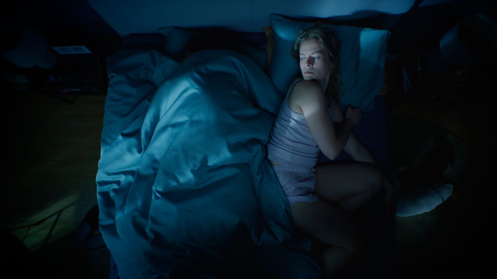 a woman sitting in a bed with a blue comforter