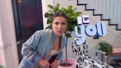 a woman standing next to a plant in a room