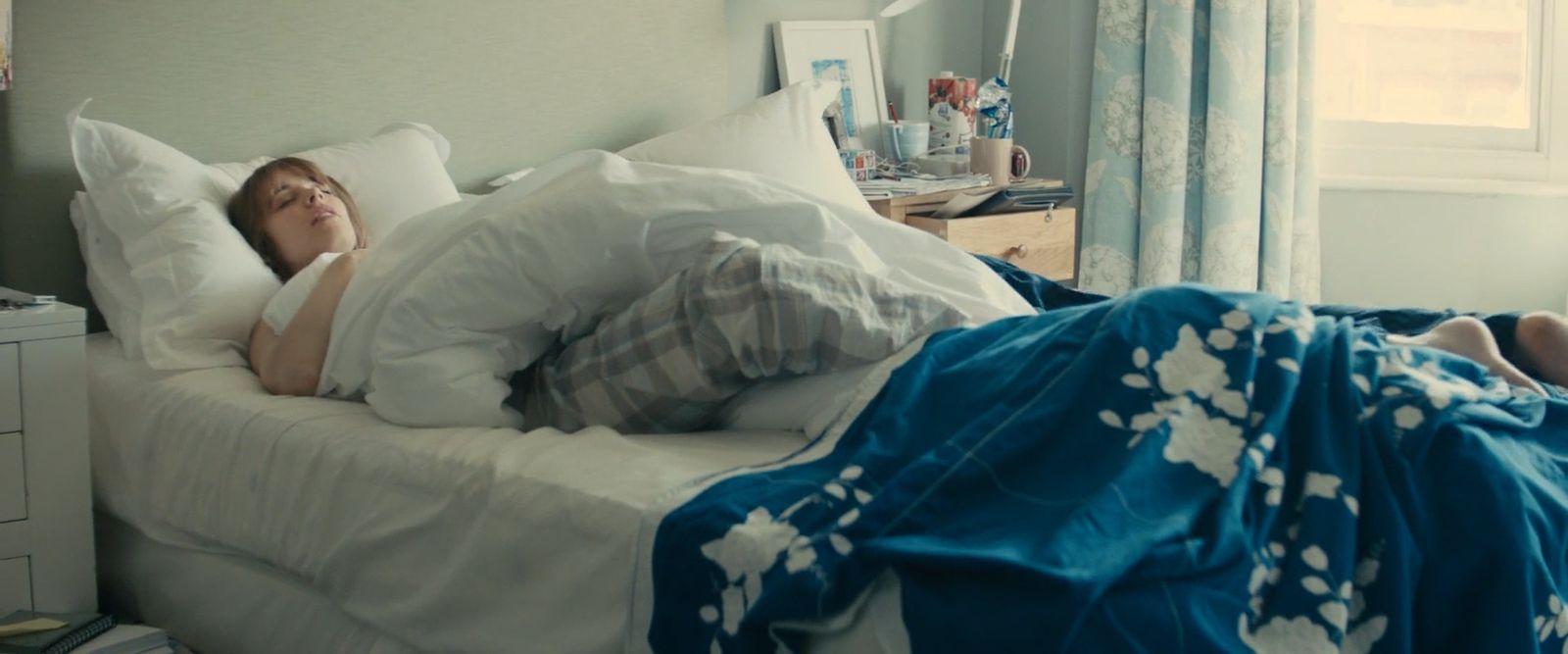 a woman laying in bed with her head on the pillow