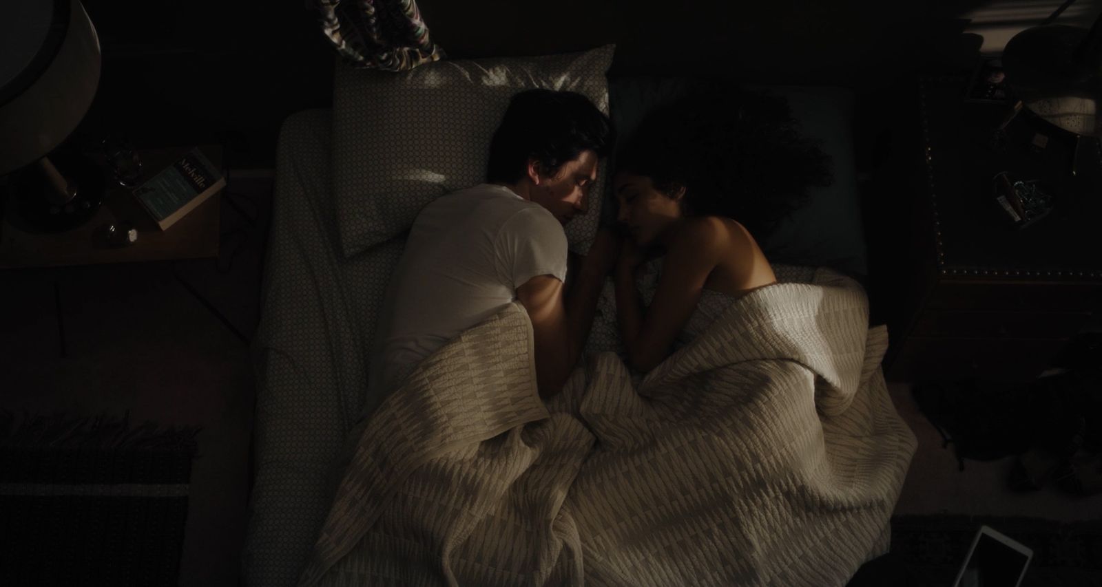 a man and woman laying in bed under a blanket