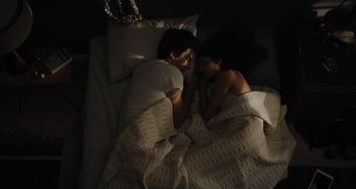 a man and woman laying in bed under a blanket