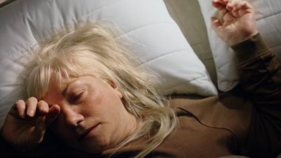 a woman laying on a bed with her eyes closed