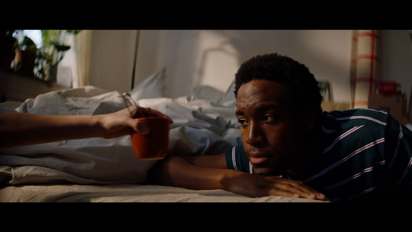 a man laying in bed holding a glass of orange juice