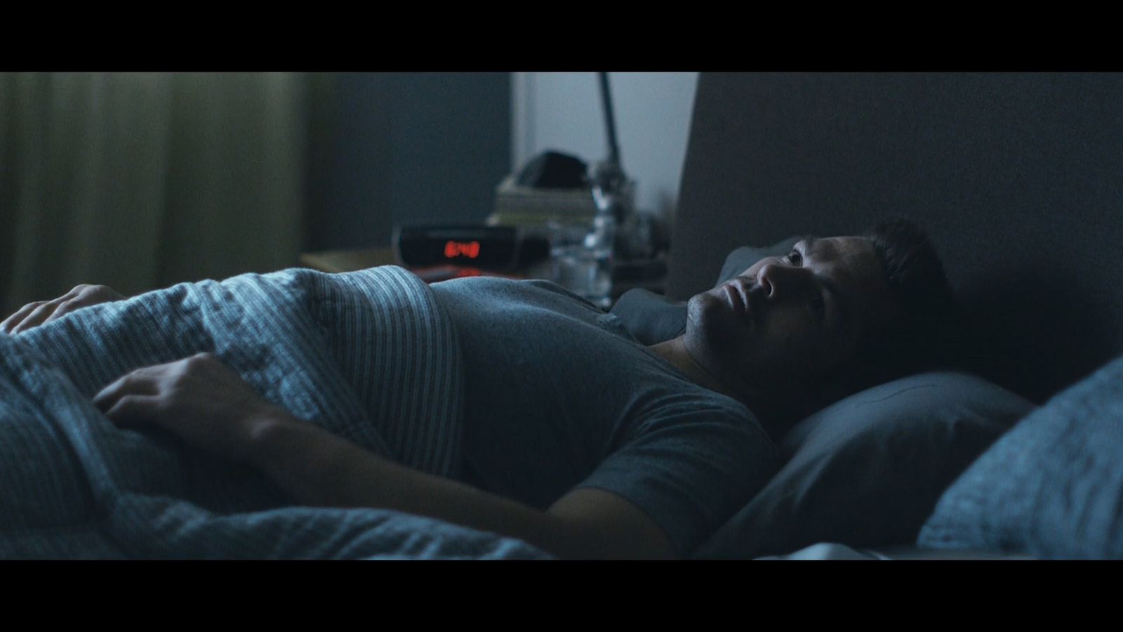 a man laying in bed with his head on the pillow