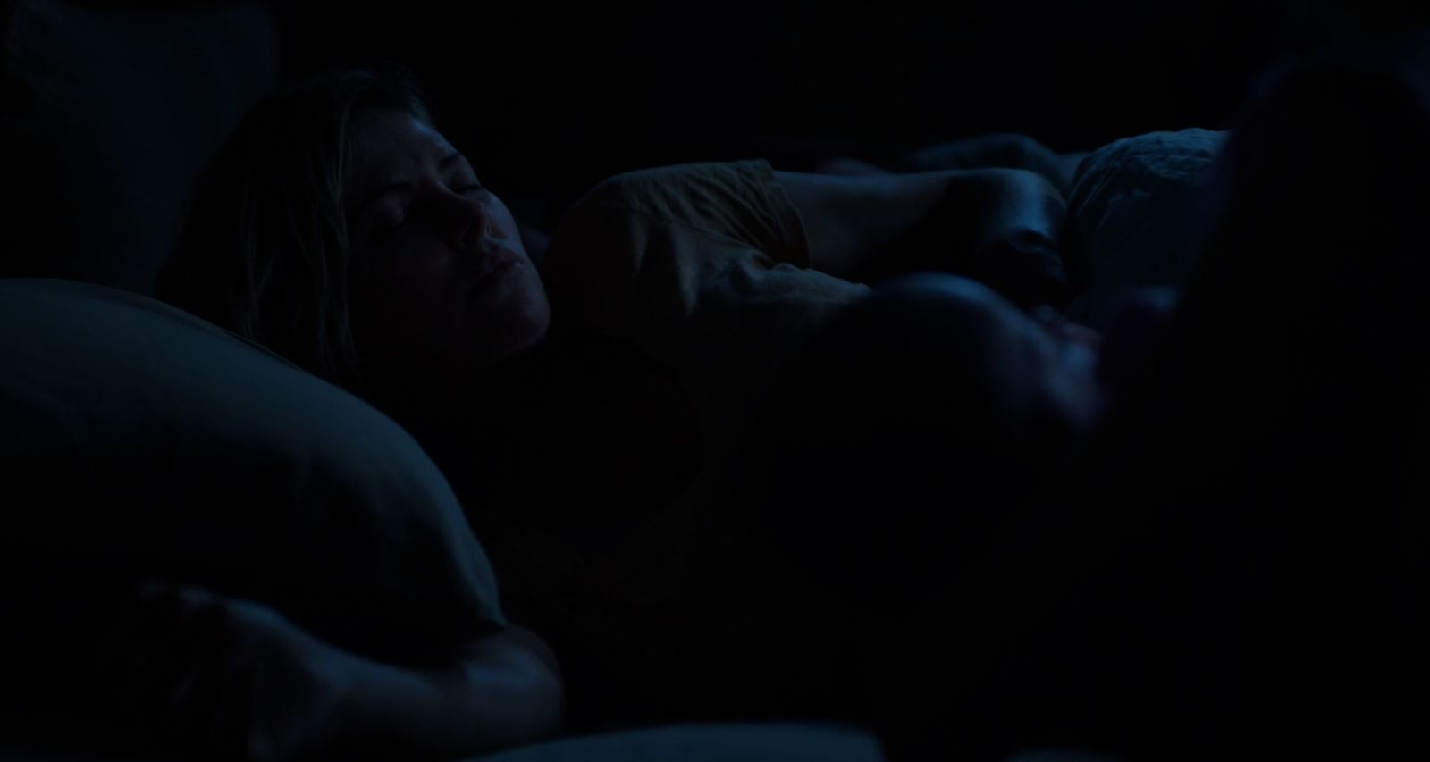 a woman laying in bed in the dark