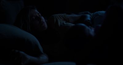 a woman laying in bed in the dark