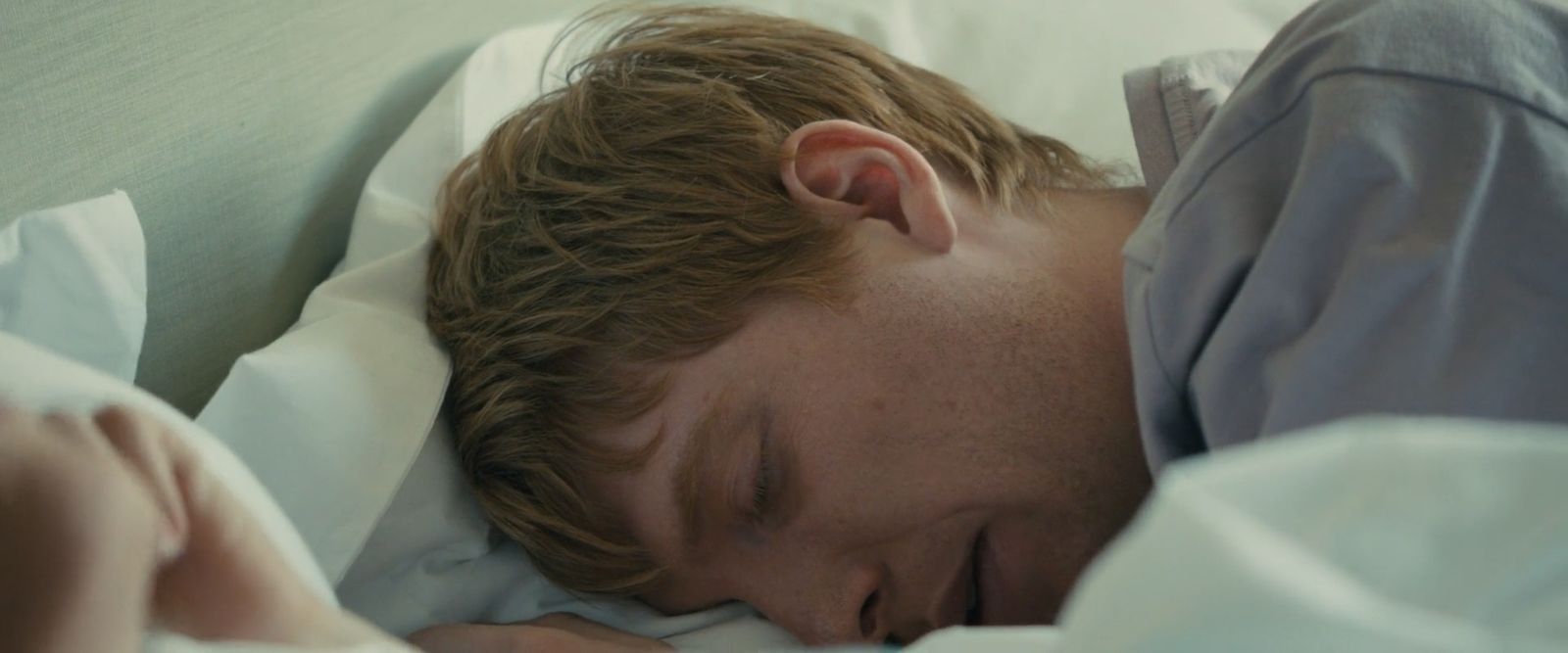 a man sleeping in bed with his eyes closed