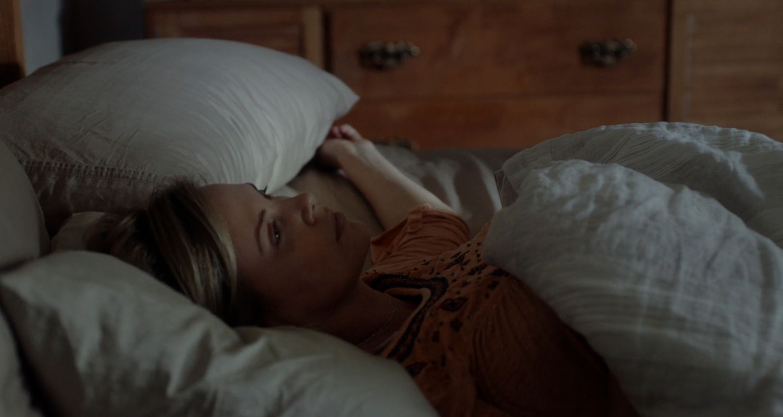 a woman laying in bed under a white pillow