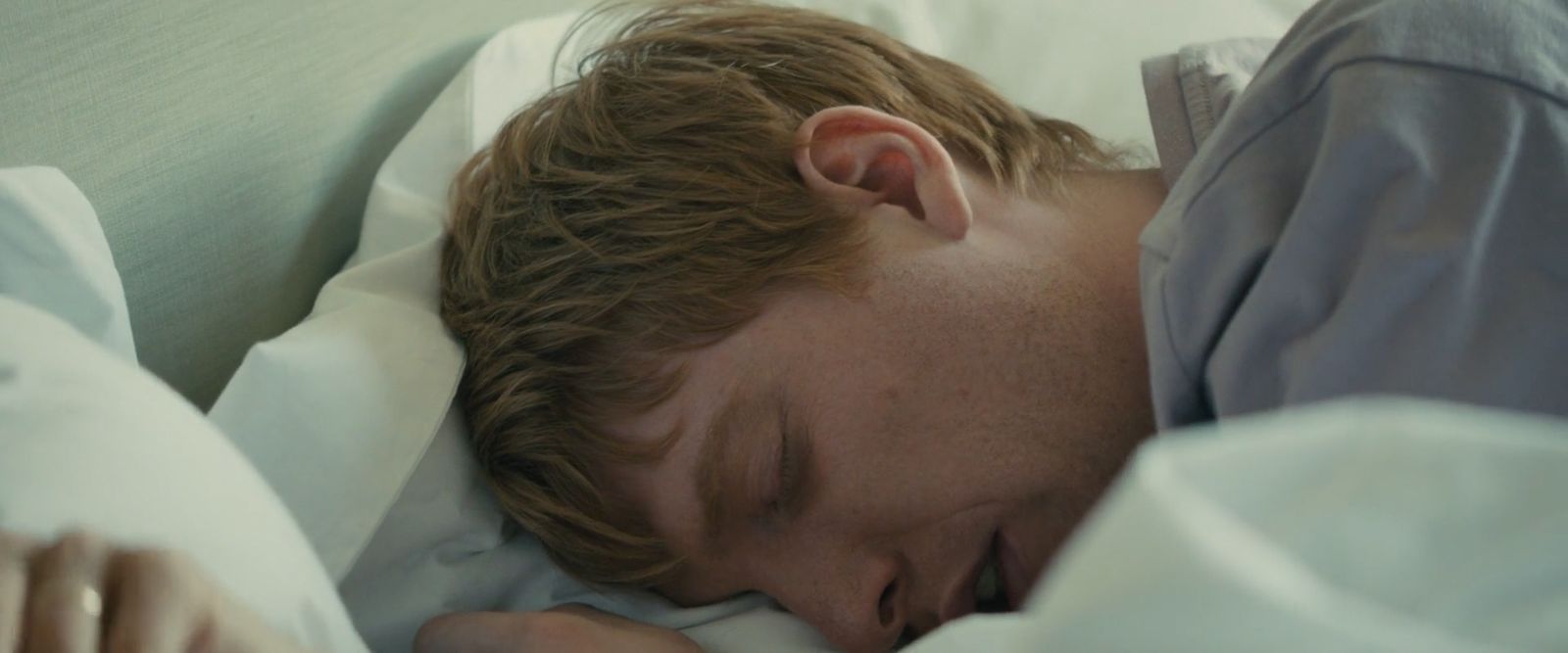 a man sleeping on a bed with white sheets