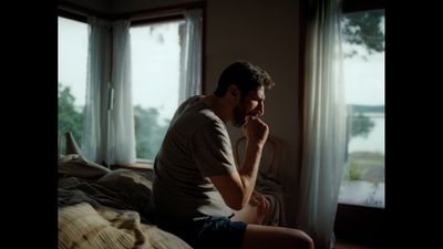 a man sitting on top of a bed next to a window