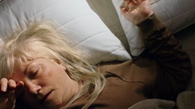 a woman laying on top of a bed next to a pillow