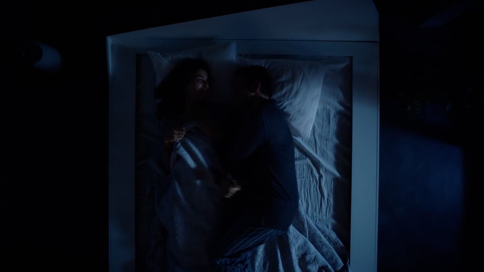 a man and a woman in a bed in the dark