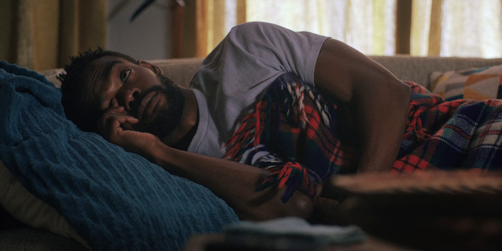 a man laying on top of a couch next to a window