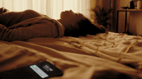 a person laying on a bed with a cell phone