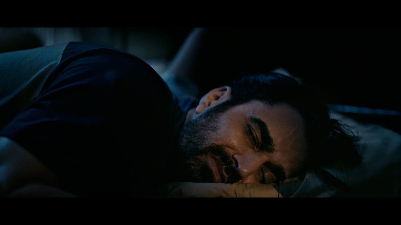 a man laying in bed with his eyes closed