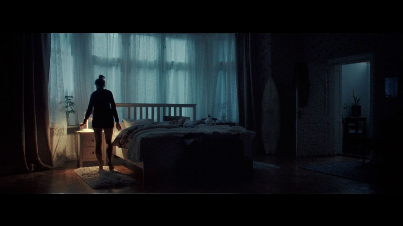 a person standing in a dark room next to a bed