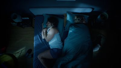 a couple of people laying in a bed in the dark