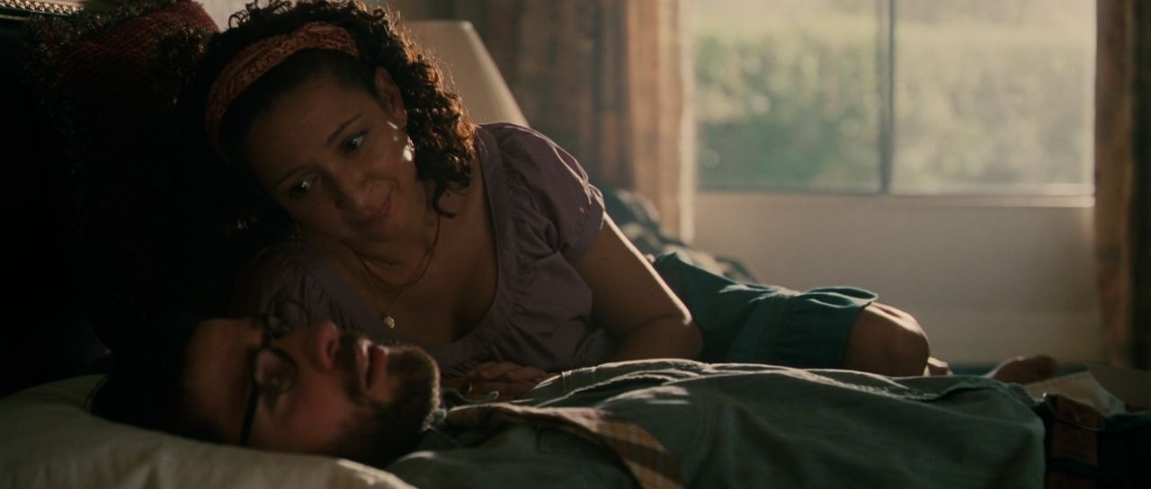 a woman laying on a bed next to a man