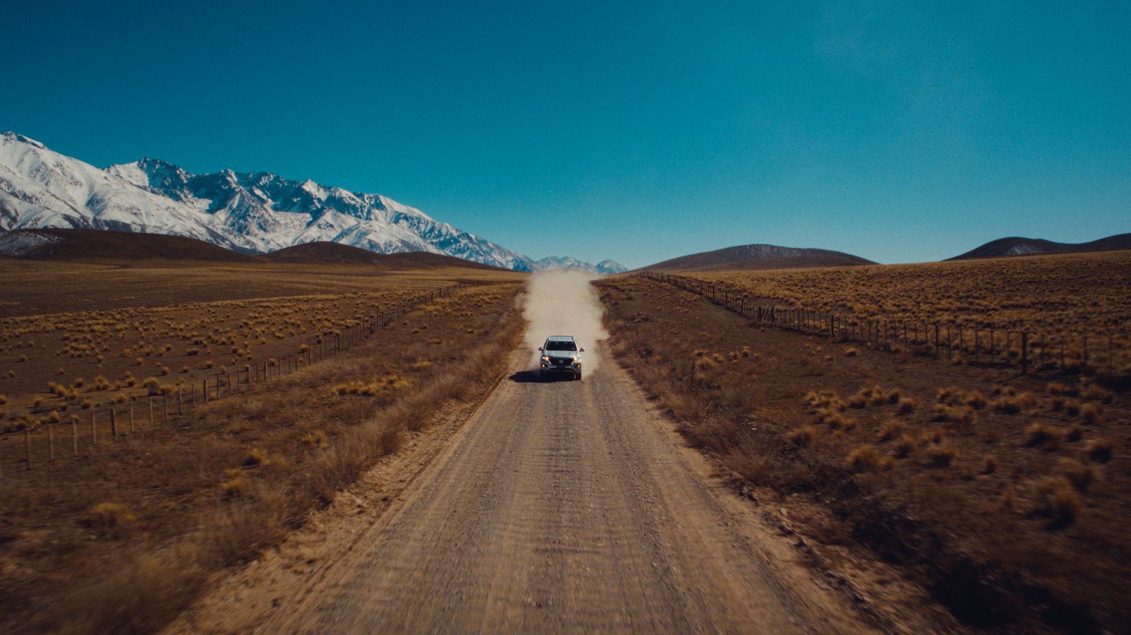 a truck driving down a dirt road in the middle of nowhere