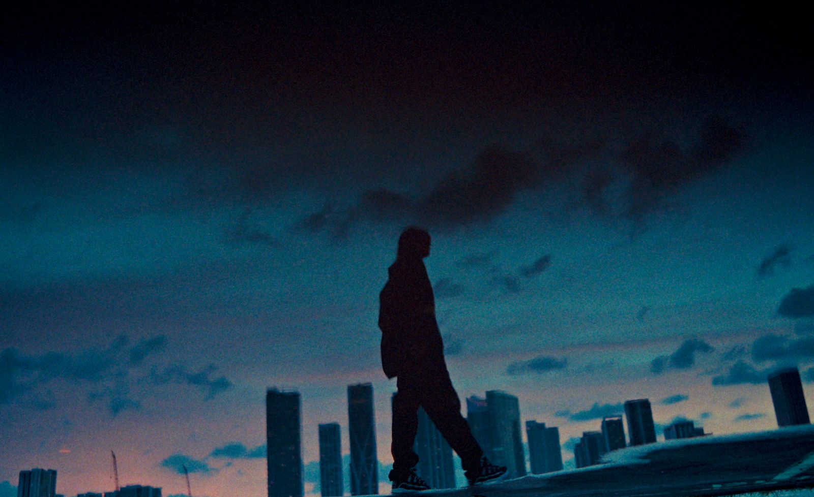 a person walking on a sidewalk in front of a city skyline