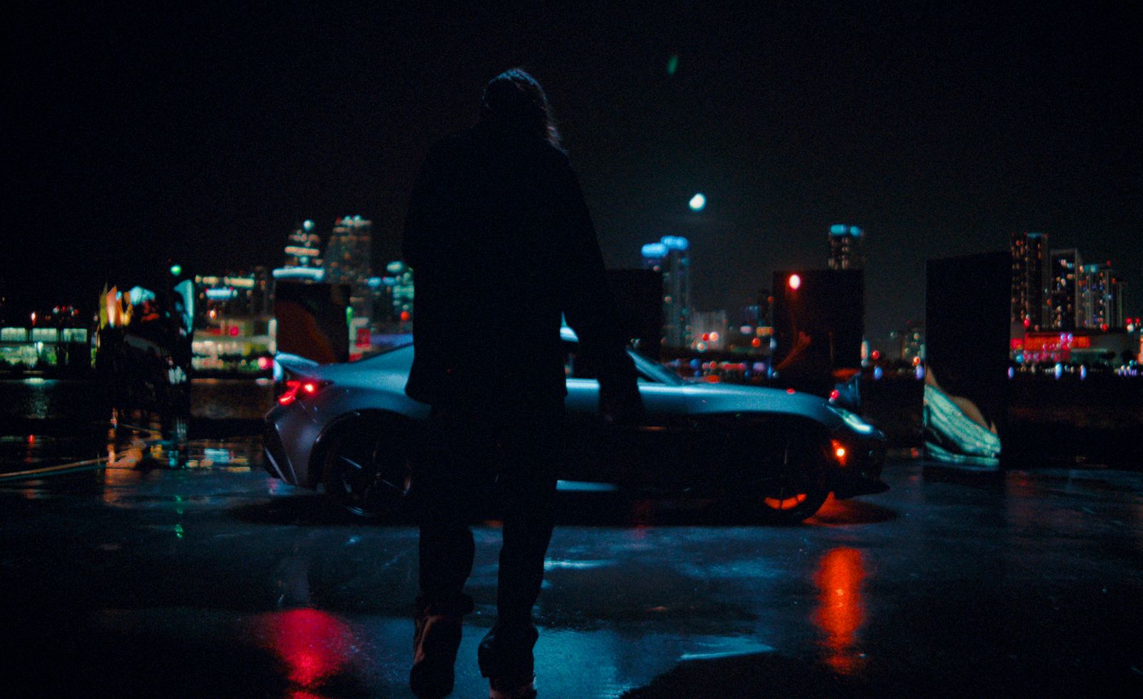 a man standing next to a parked car at night