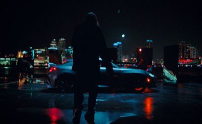 a man standing next to a parked car at night