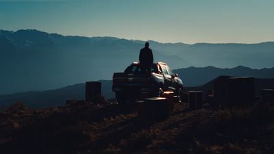 a man standing on top of a truck in the mountains