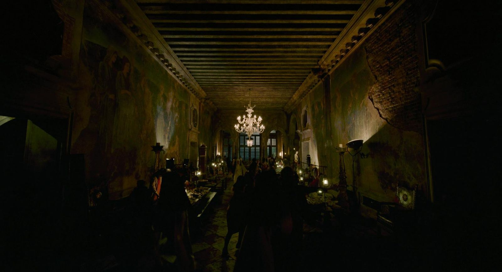 a dark hallway with a chandelier hanging from the ceiling