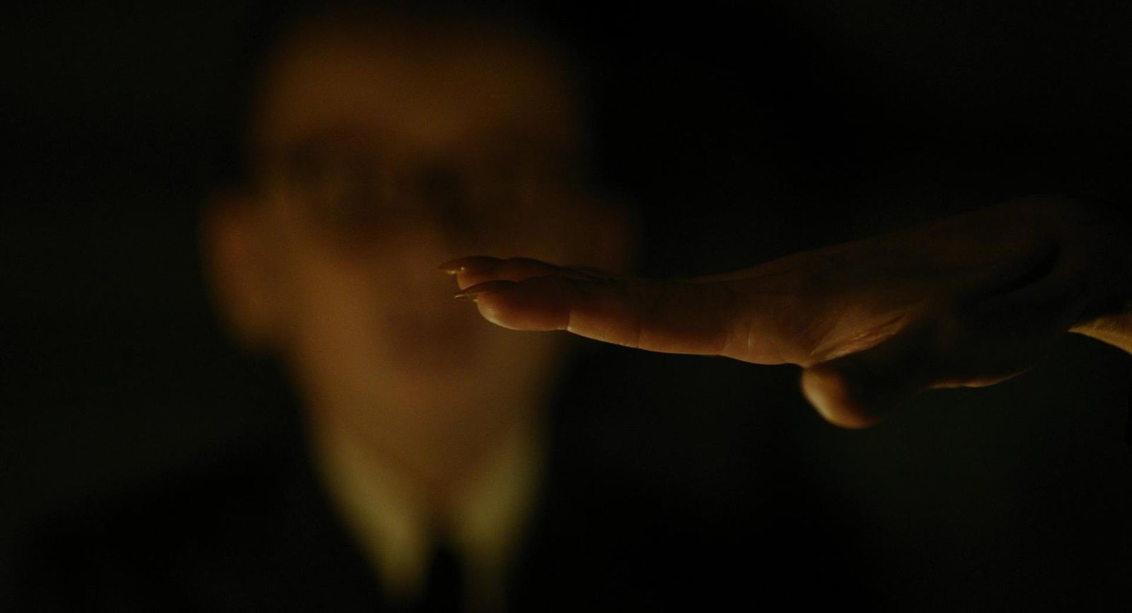 a man in a suit pointing at something in the dark