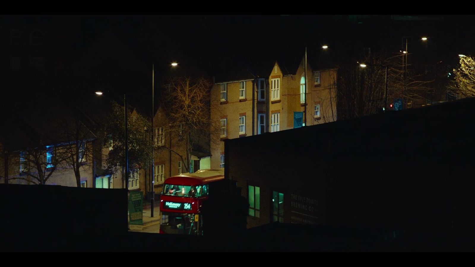 a red double decker bus driving down a street at night