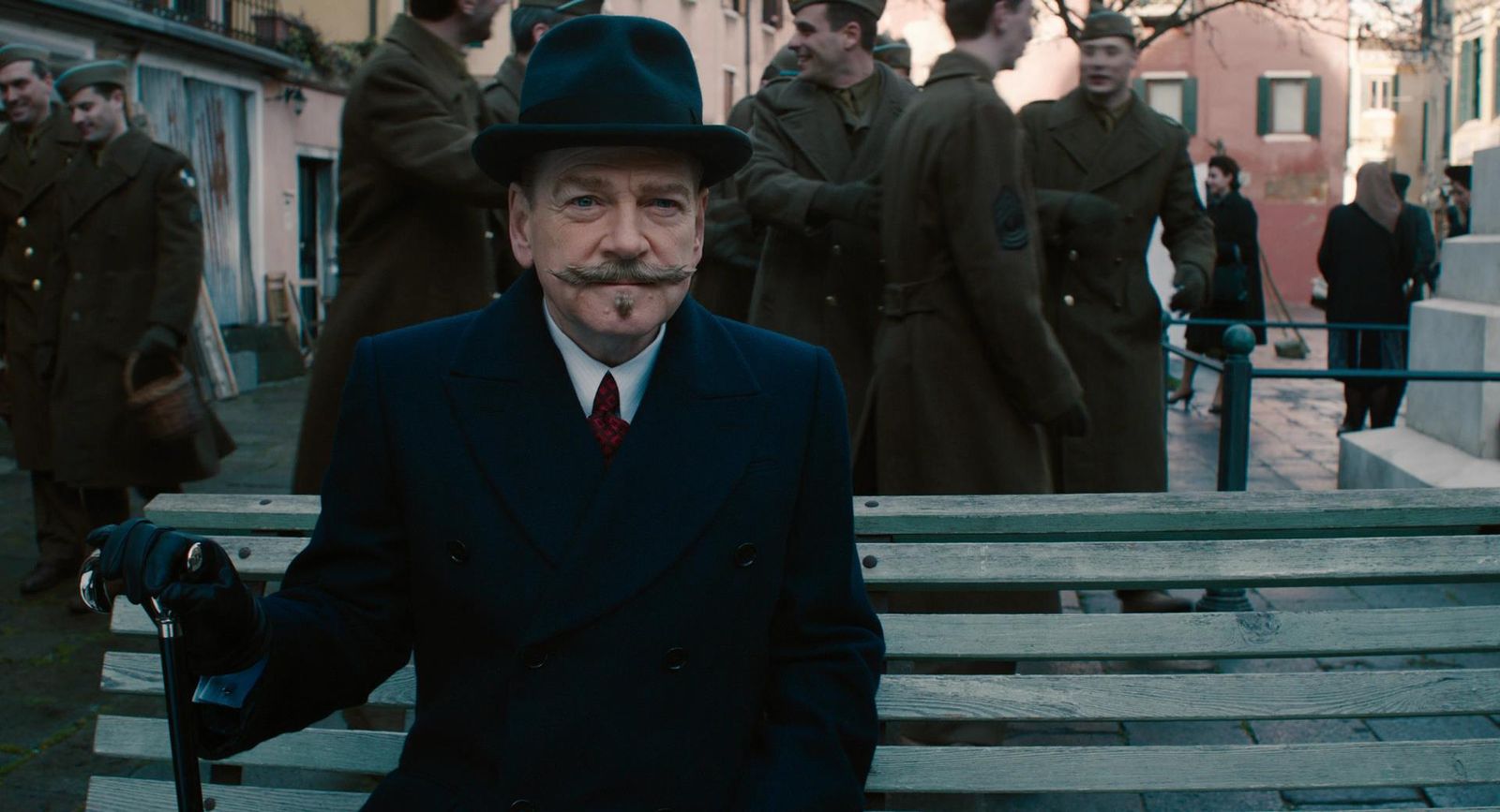 a man in a suit and hat sitting on a bench