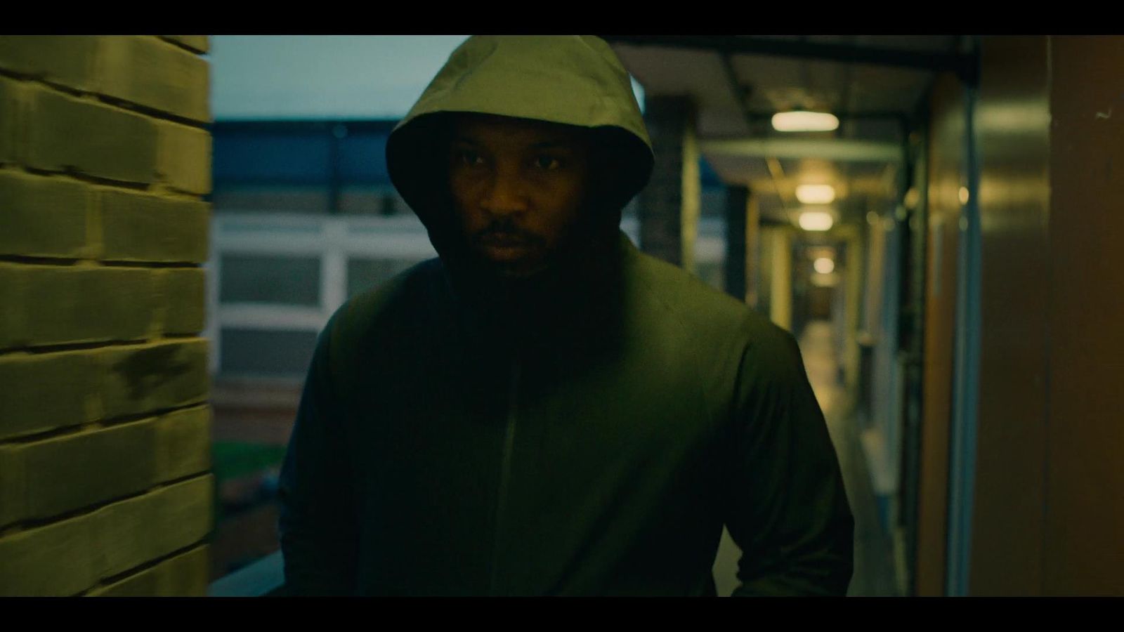 a man in a hoodie standing in a hallway