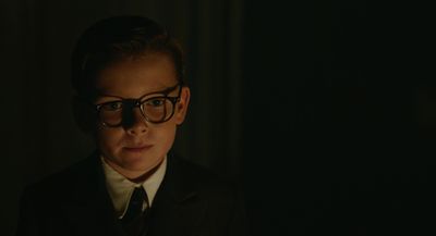 a man wearing glasses and a suit in a dark room