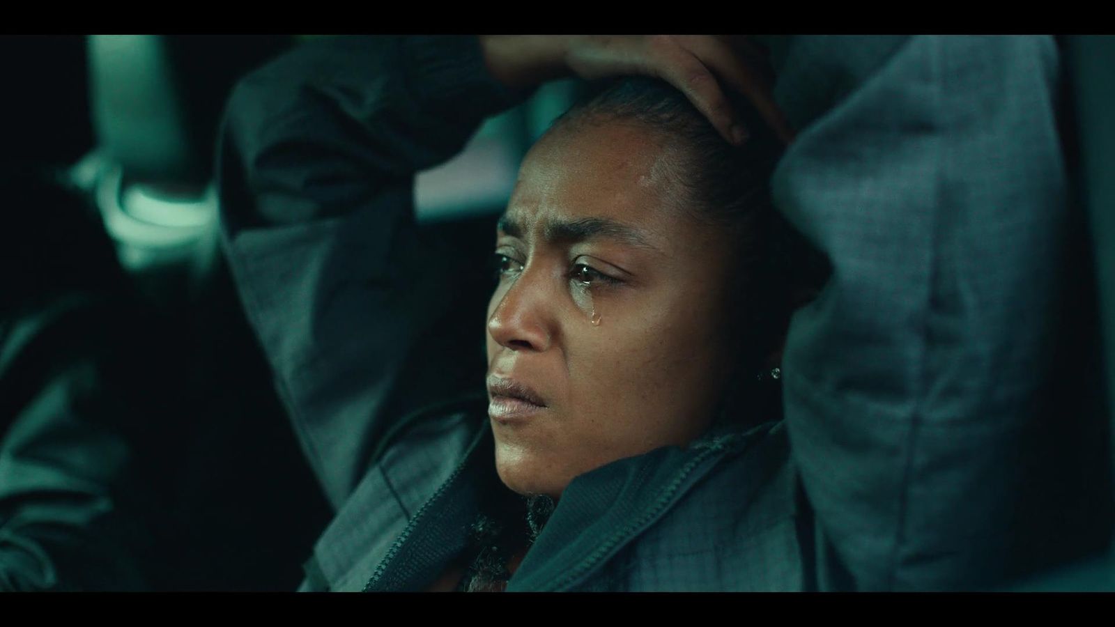 a woman sitting in a car with her hand on her head