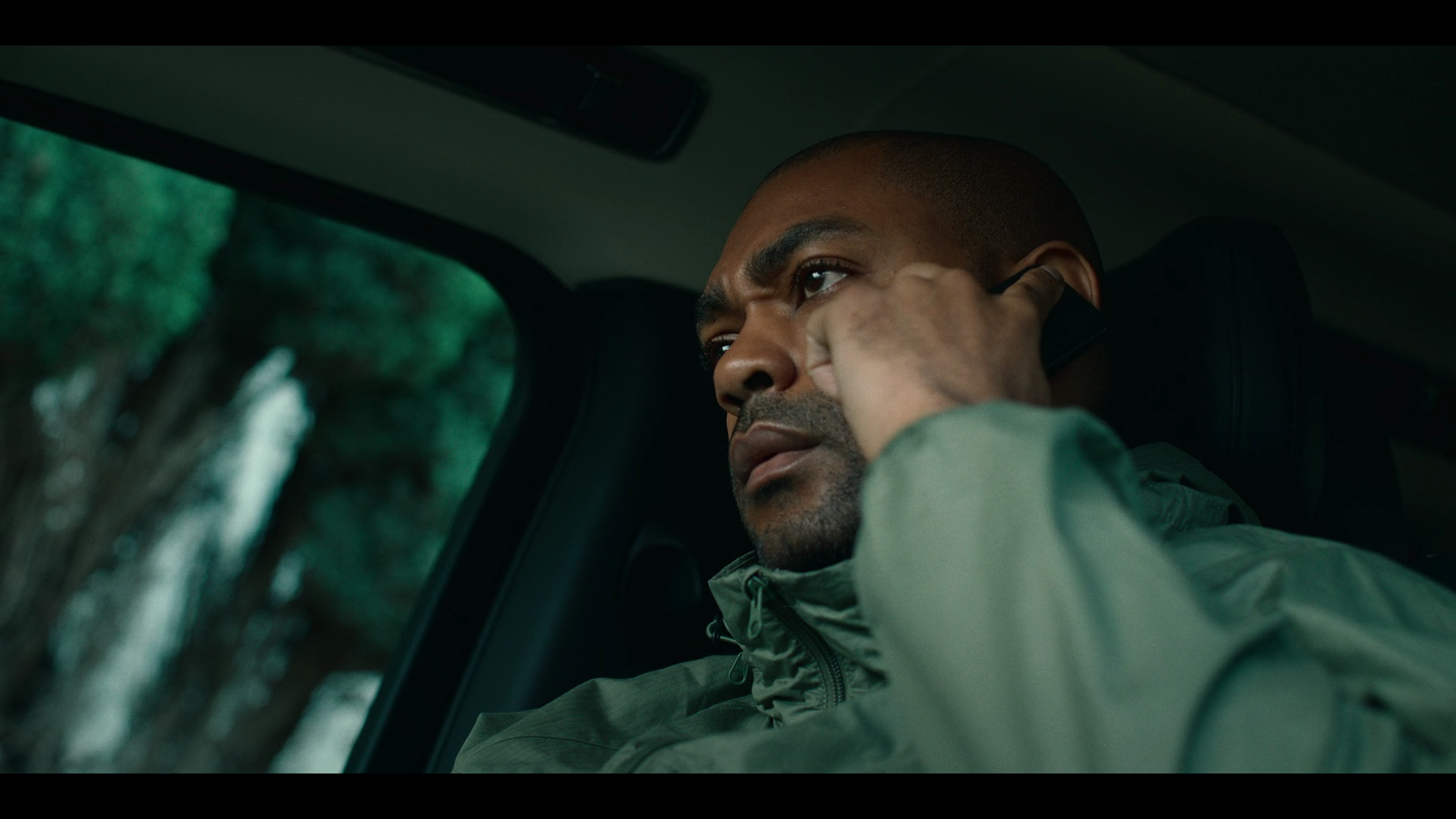 a man sitting in a car talking on a cell phone