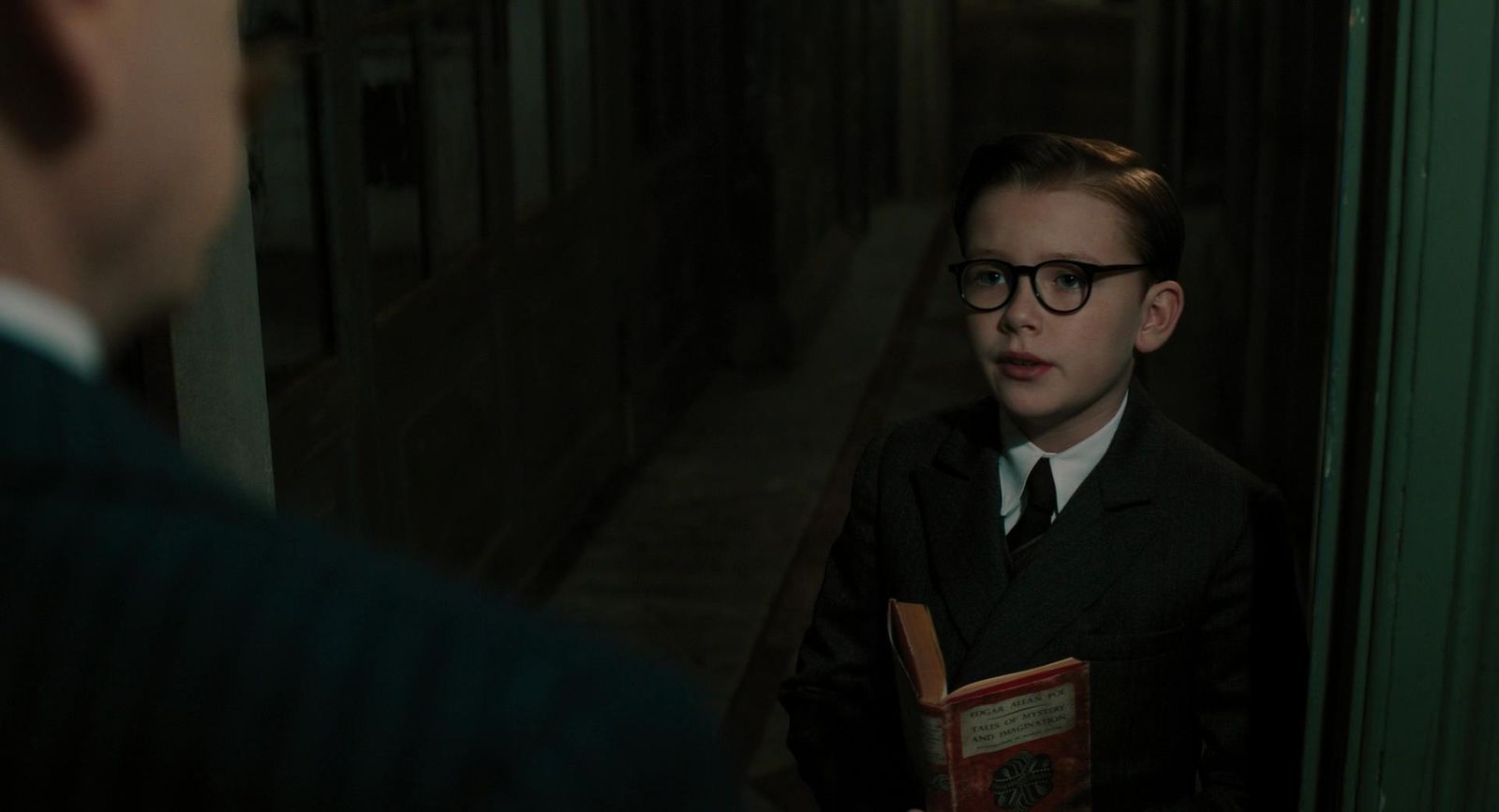 a boy in a suit and tie holding a book