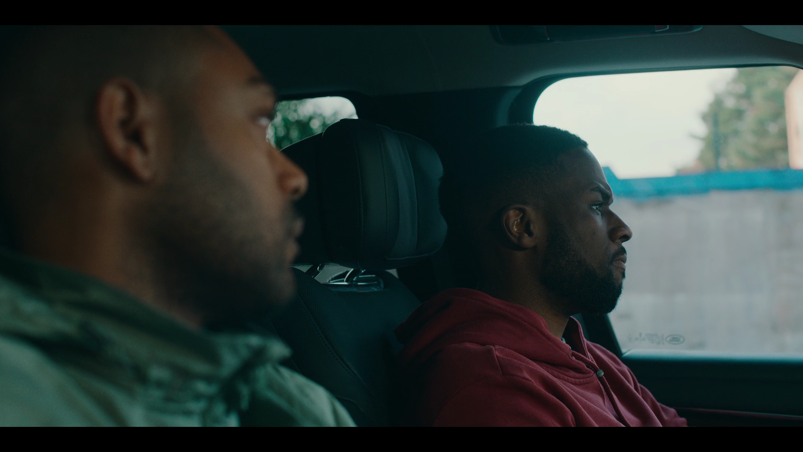 two men sitting in a car looking out the window