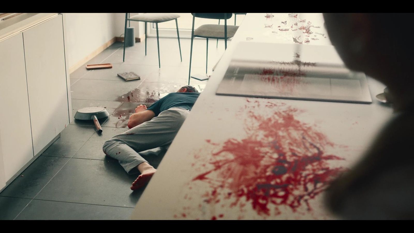 a man laying on the floor next to a counter